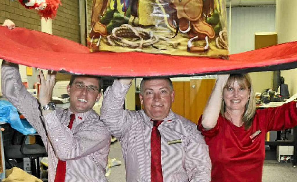 Dom Benz, Bevan Henningsen and Jen Beattie try on their larger-than-life rodeo hat which will be displayed in the shop front by tomorrow.